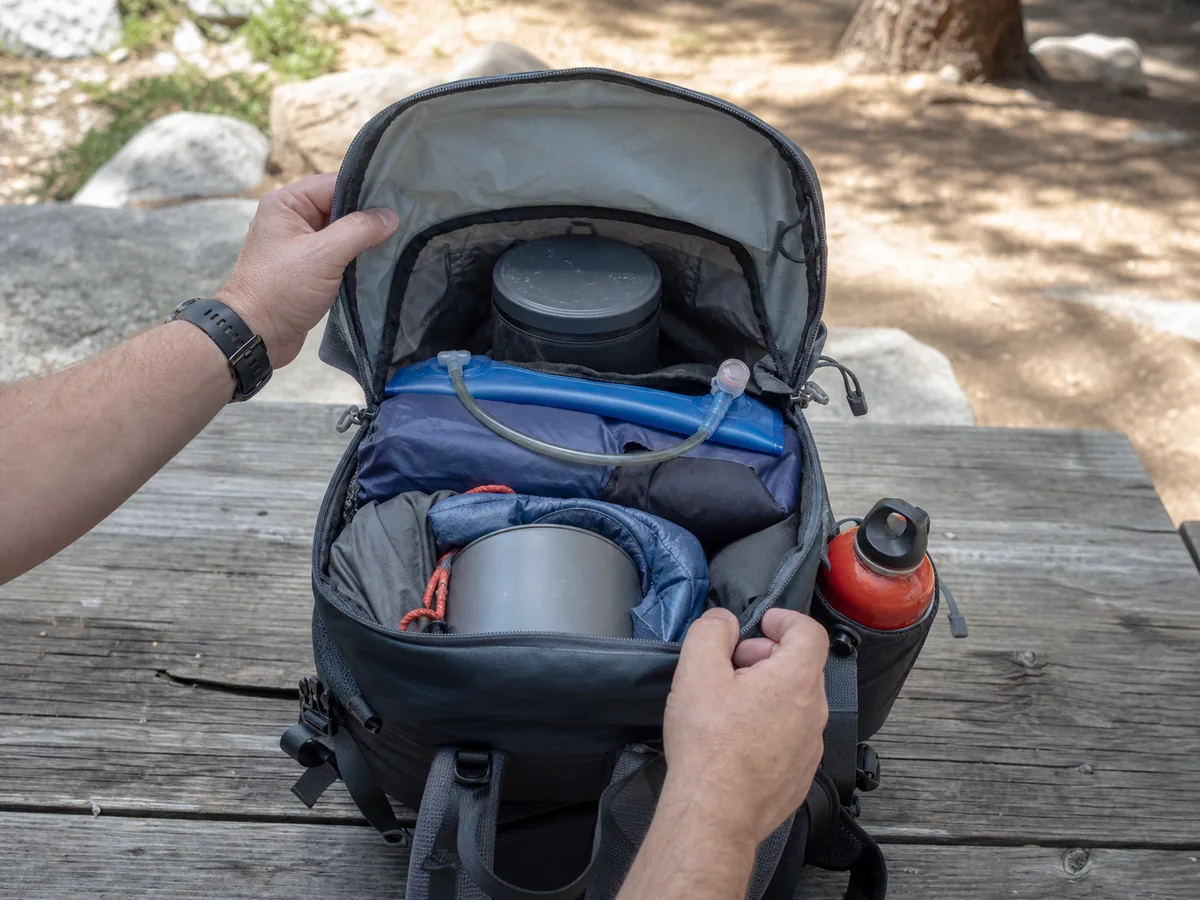 Backpack with a centered food canister water reservoir and isolated upright fuel bottle arranged close to the spine - dense item placement | KnowOutdoor