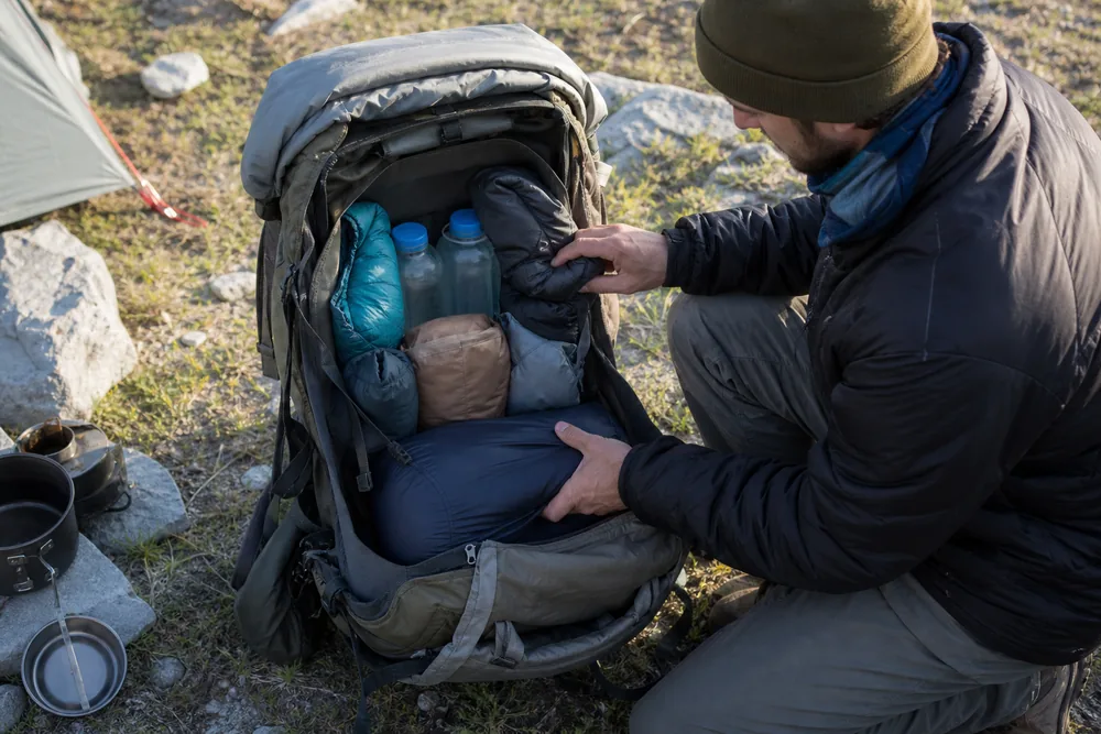 Backpacker rebuilding the dense core around reduced food and refilled water before leaving camp