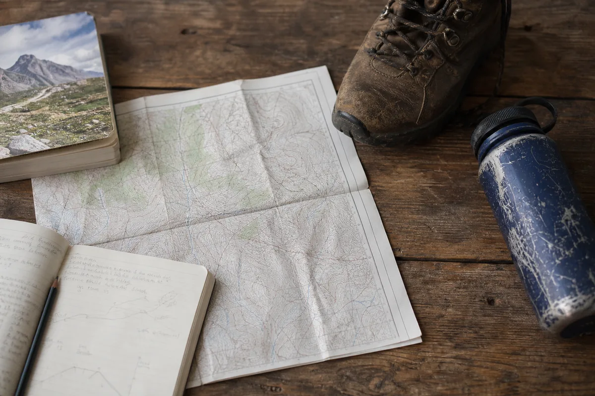Day-hike planning flatlay with a topographic map, route notes, a worn boot, and a water bottle - Park ranking criteria | KnowOutdoor
