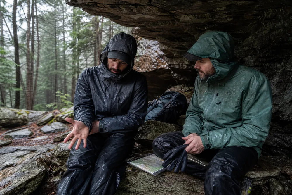 Rain-soaked hiking partners under shelter checking hand coordination, speech, dry gloves, and the shortest route back
