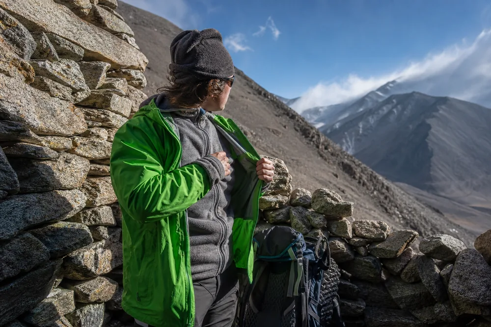 Trekker opens shell vents and removes a fleece before a sustained high-altitude climb - Uphill ventilation | KnowOutdoor