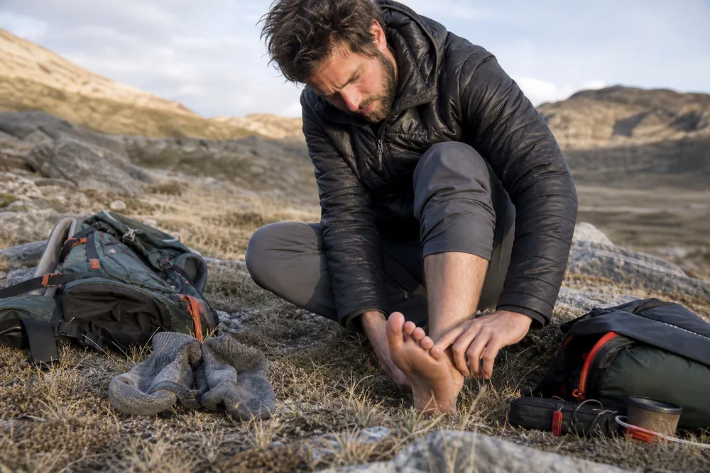 Trekker checks heels, toes, nails, and the spaces between toes beside dry socks and a compact foot-care kit - Morning foot check | KnowOutdoor