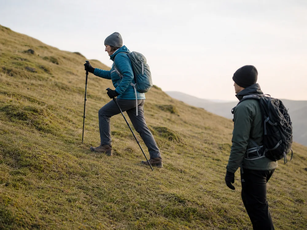 Trekker practices counted rest steps on a safe grassy slope with poles and a light pack - Rest step practice | KnowOutdoor
