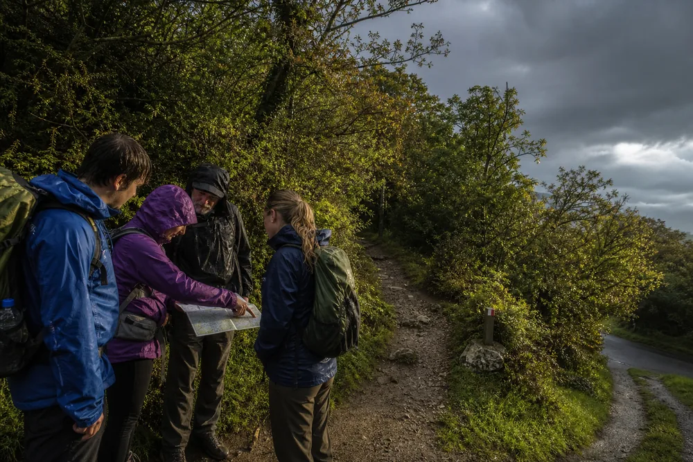 Trekking group choosing a marked lower exit while daylight and calm weather remain