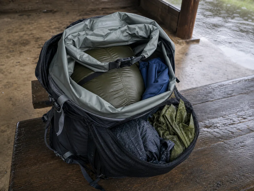 Open trekking pack with waterproof liner sealed sleep bag and wet rain shell stored outside the dry core